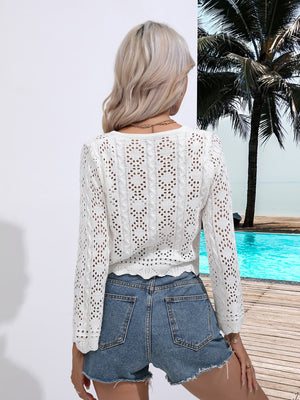 White lace-inset cardigan with open knit pattern and scalloped hem, styled with denim shorts.