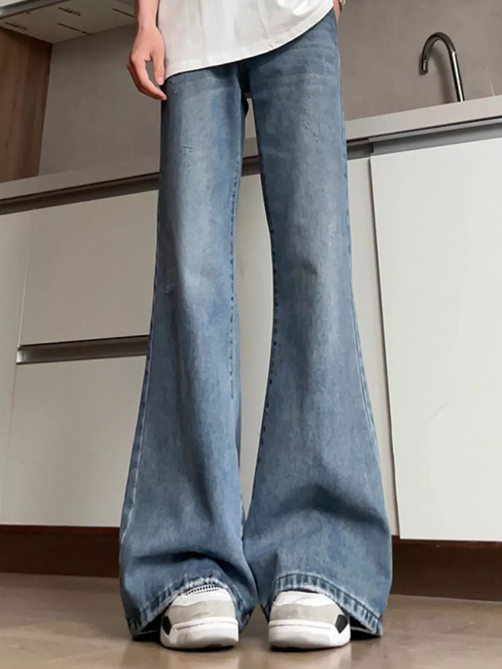 Distressed full-length flare jeans in light blue denim with a wide leg opening.