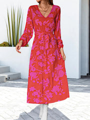 Tiered floral midi dress with tie waist in red and pink bloom pattern, V-neck, long sleeves.