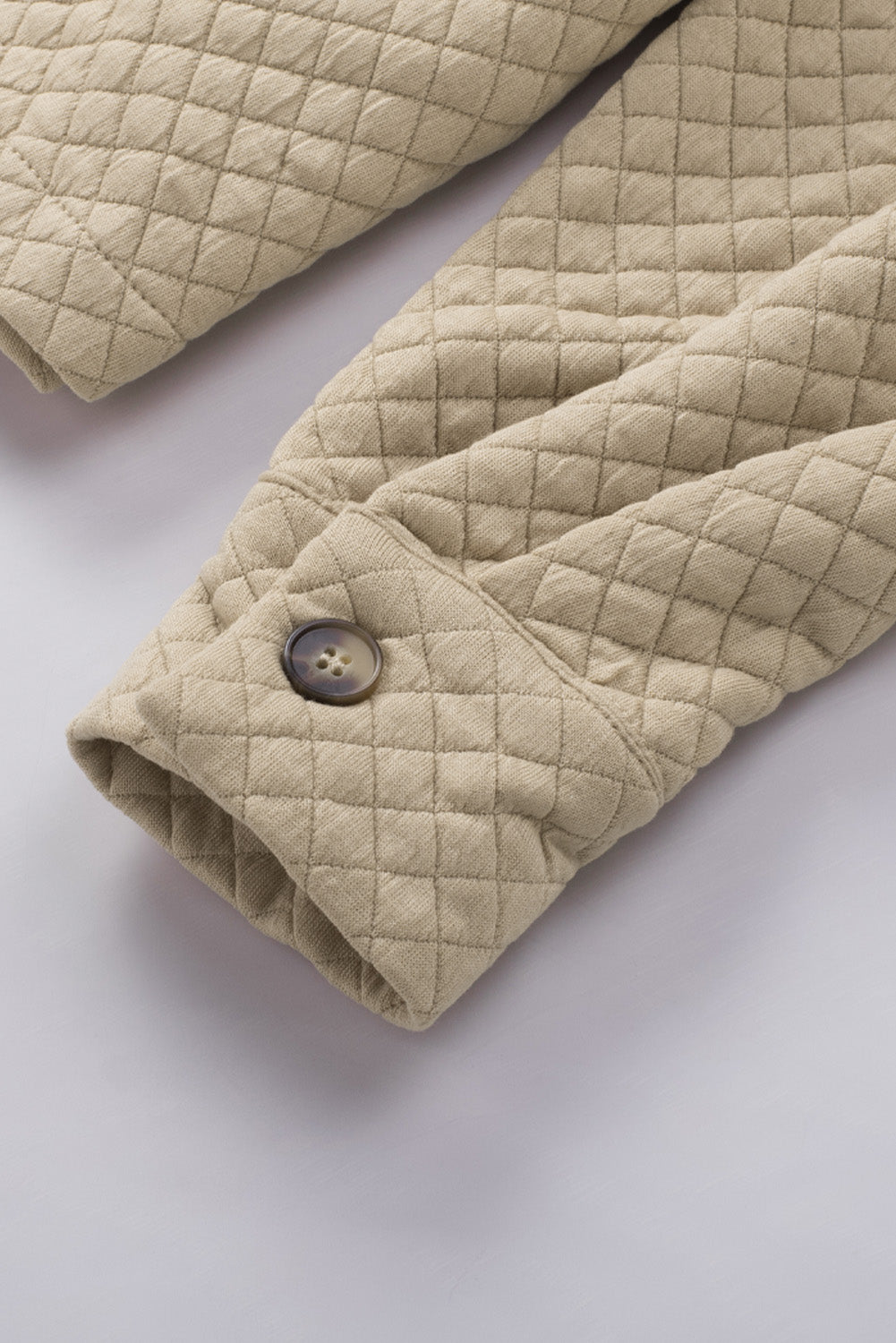 Tan quilted overshirt detail showing diamond pattern and button cuff.
