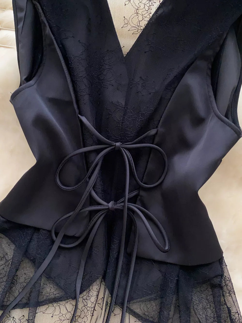 Black lace-embellished button-down vest coat with satin panels and lace-up back detail.