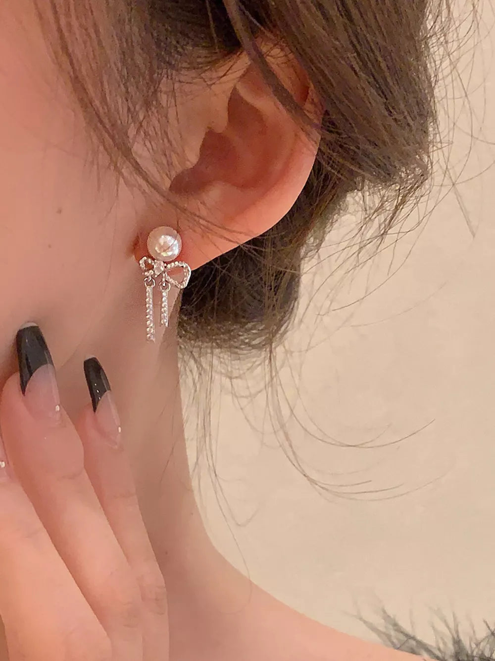 Luminous pearl drop earrings with bowknot and crystal fringe detail.