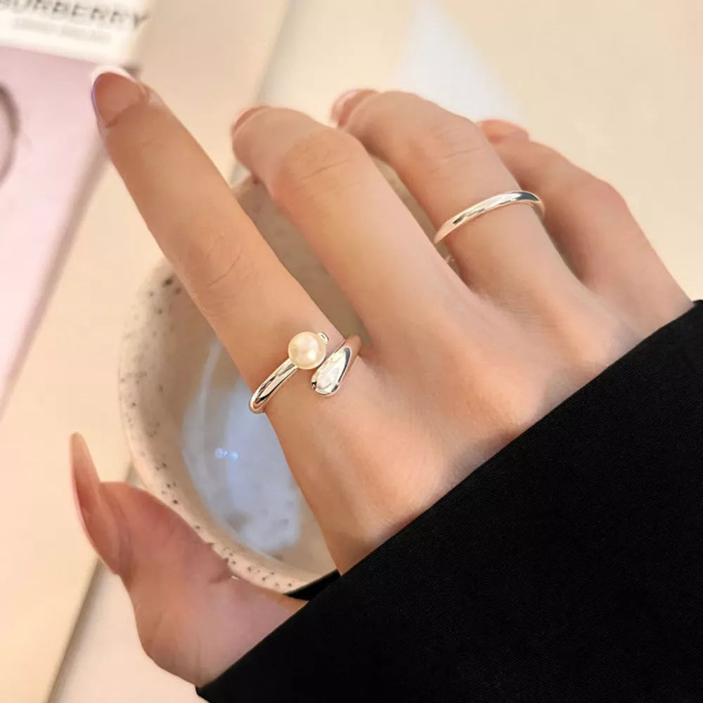 Luminous pearl bypass ring in silver with abstract detail.