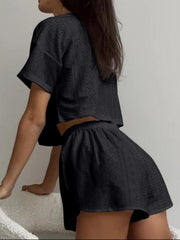 Black perforated crop top and shorts set with short sleeves and elastic waist.