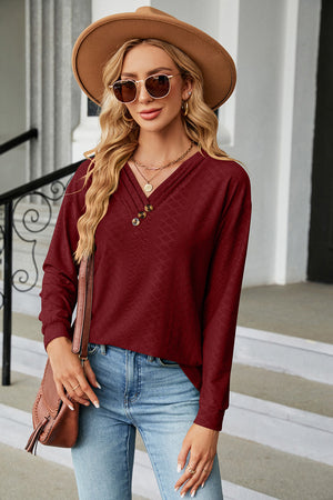Burgundy textured henley v-neck top with button detail and long sleeves.