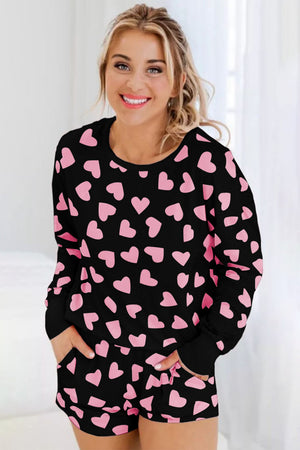 Black pajama set with pink heart print, long sleeves, crew neck, and shorts with pockets.