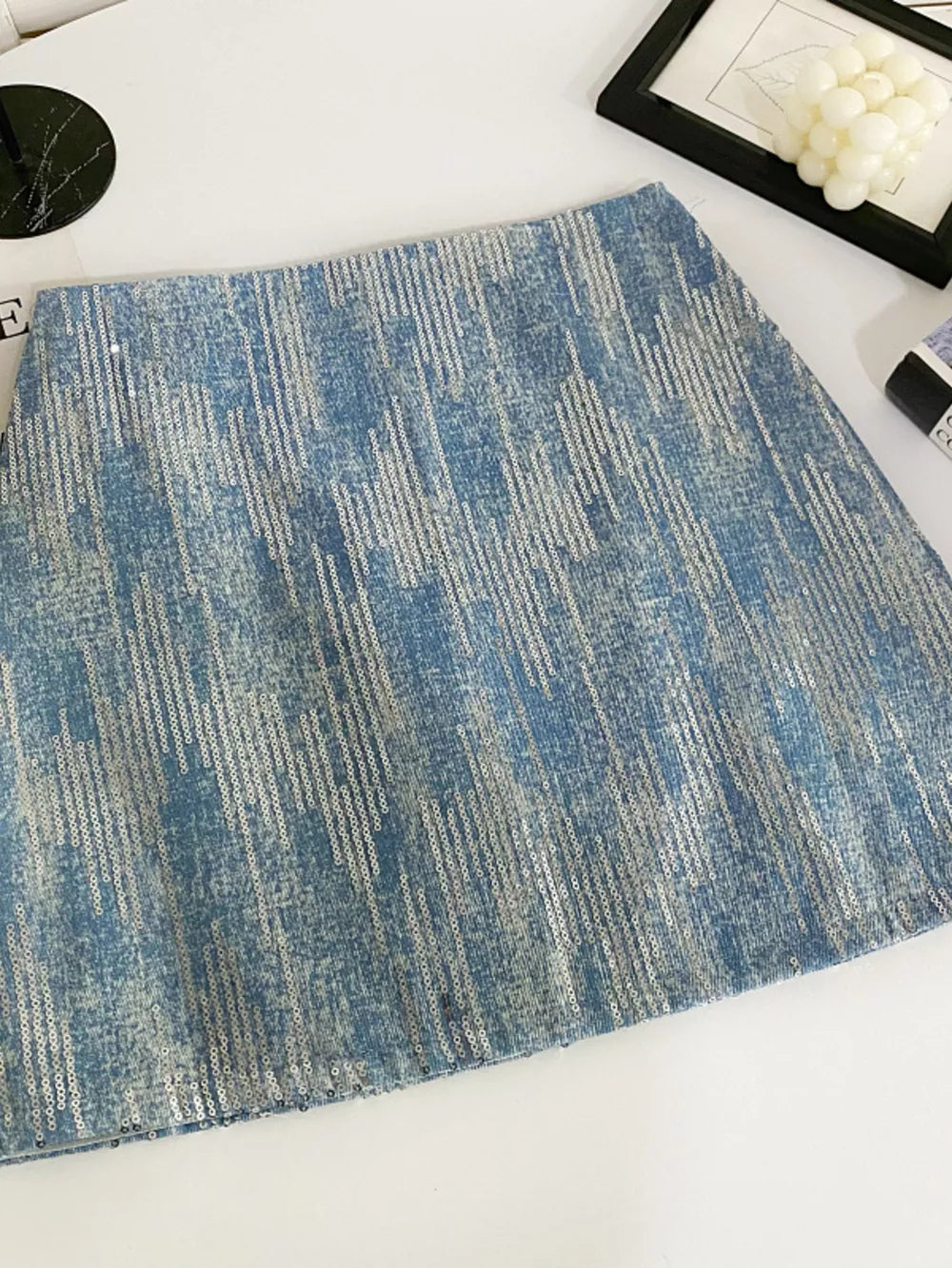 Light blue sequin mini skirt with a distressed denim look and vertical sequin stripes.