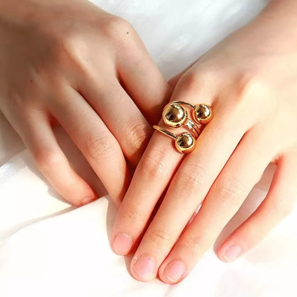 Gold multi-layered ball ring with a modern, abstract design.