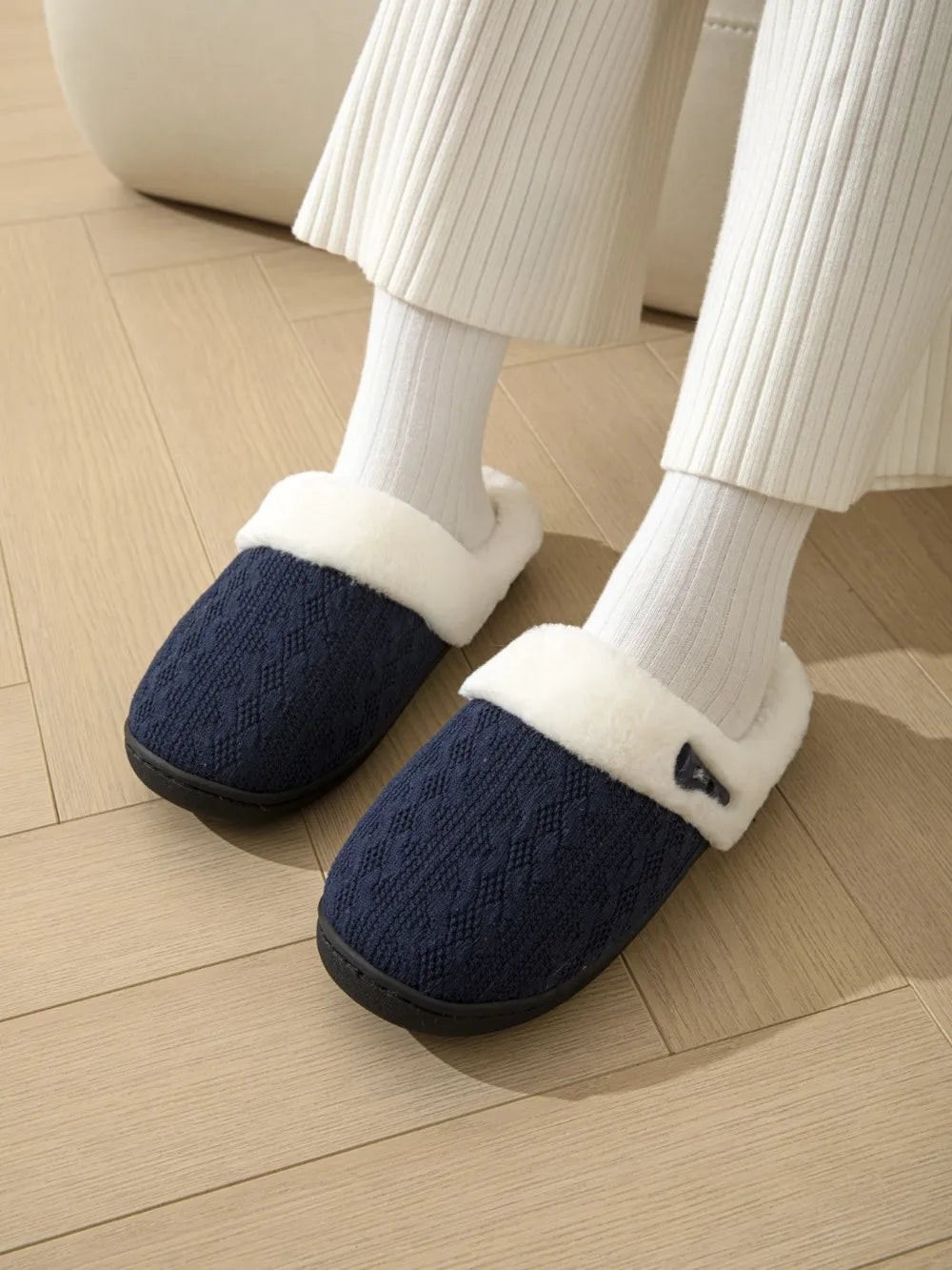 Dark Navy cable knit slippers with white shearling lining and black soles.