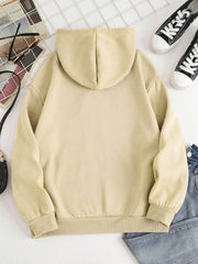 Oversized beige hoodie with pouch pocket and ribbed cuffs, styled with jeans and sneakers.