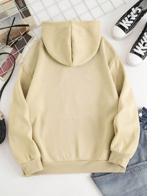 Oversized beige hoodie with pouch pocket and ribbed cuffs, styled with jeans and sneakers.