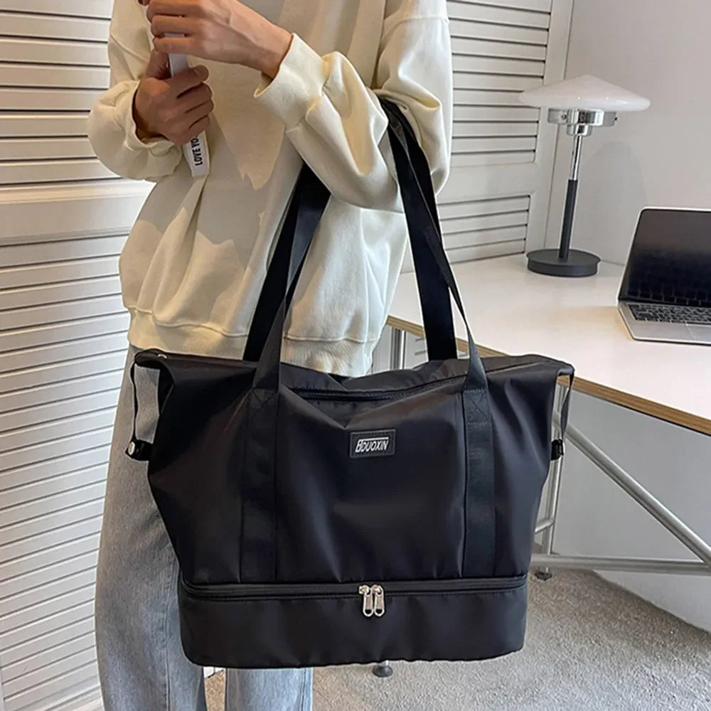 Black dual-compartment travel tote with metallic trim and dual zippers.
