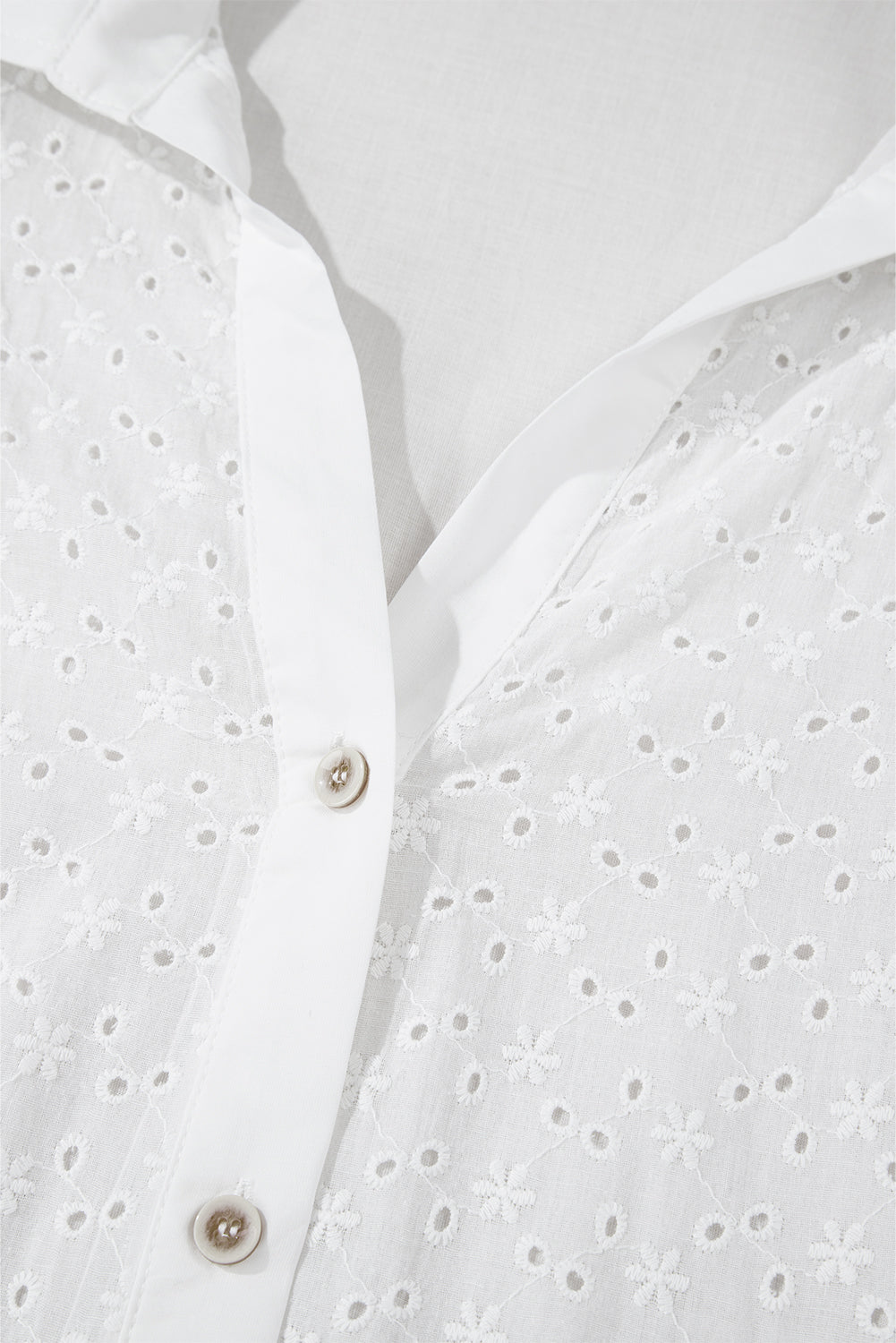 White eyelet blouse with embroidered floral details and button front.