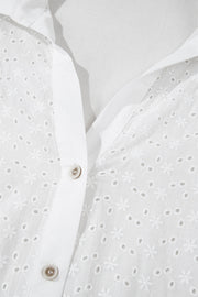 White eyelet blouse with embroidered floral details and button front.
