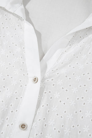 White eyelet blouse with embroidered floral details and button front.