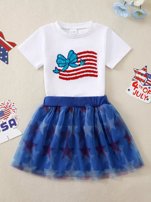 White cotton tee with American flag applique and bow, paired with a blue star-print tulle skirt.