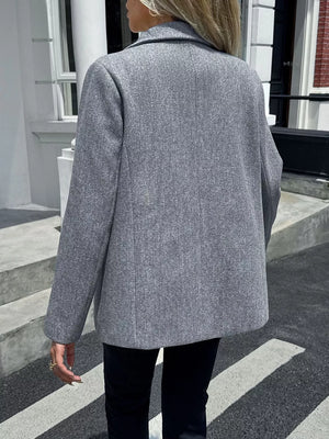 Gray lapel blazer with buttoned front and tailored fit.