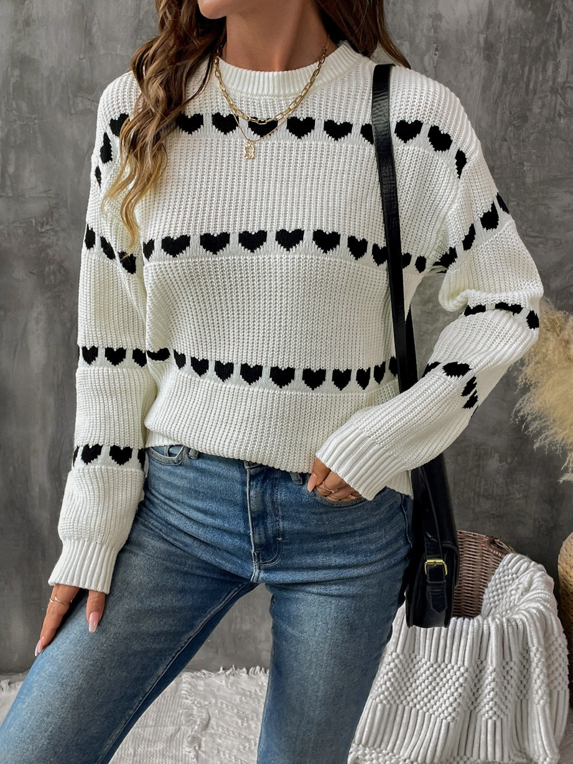 Cream knit sweater with black heart pattern, long sleeves, crew neck, casual style.