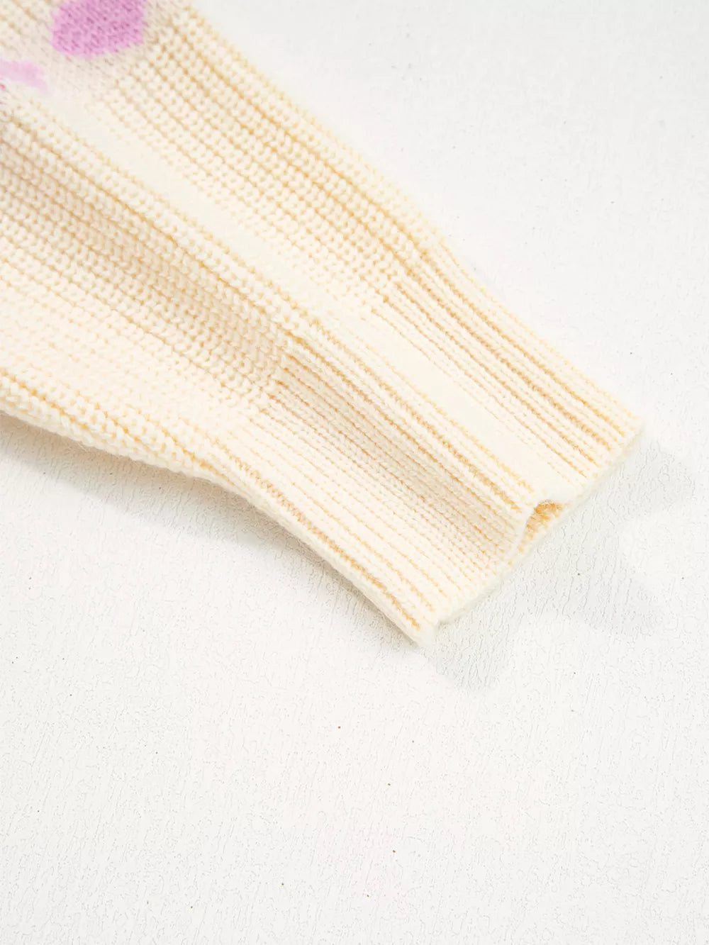 Cream knit sweater with purple heart pattern detail and ribbed cuffs.