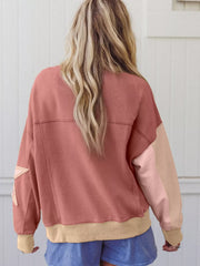 Dusty pink sweatshirt with exposed seams, star patchwork on sleeve, and contrast stitching.
