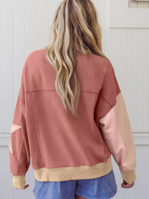 Dusty pink sweatshirt with exposed seams, star patchwork on sleeve, and contrast stitching.