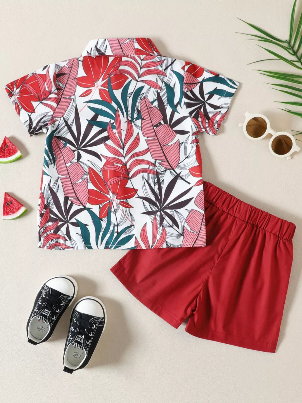 Toddler shirt and shorts set with tropical leaf print and red shorts.
