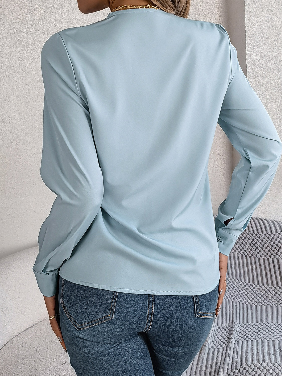 Light blue long sleeve blouse with V-neckline and button cuff detail.