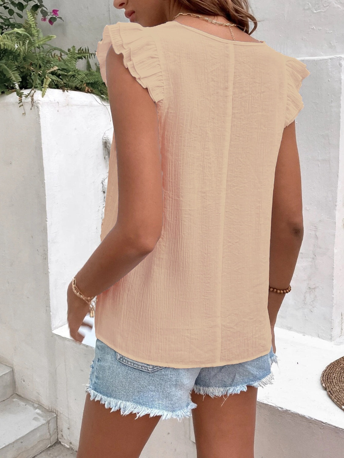 Peach embroidered trim flutter sleeve blouse with textured fabric.