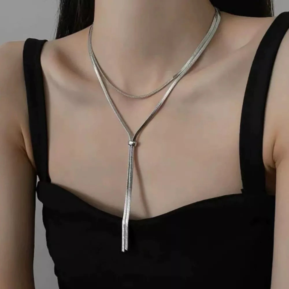 Silver layered snake chain necklace with tassel detail, a chic accessory.