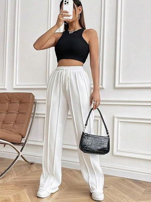 Pleated wide-leg lounge trousers in white with a drawstring waist and a relaxed fit.