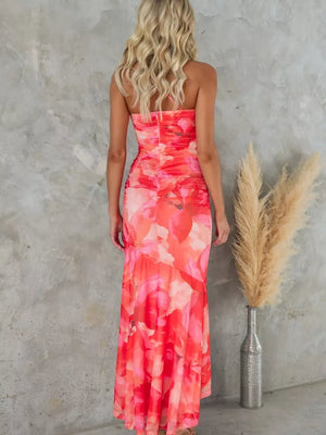 Maxi dress with floral print in red and pink, one-shoulder, ruched bodice, and flowing skirt.