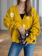 Mustard yellow oversized knit cardigan with daisy embroidery, V-neck, button front, and ribbed cuffs.