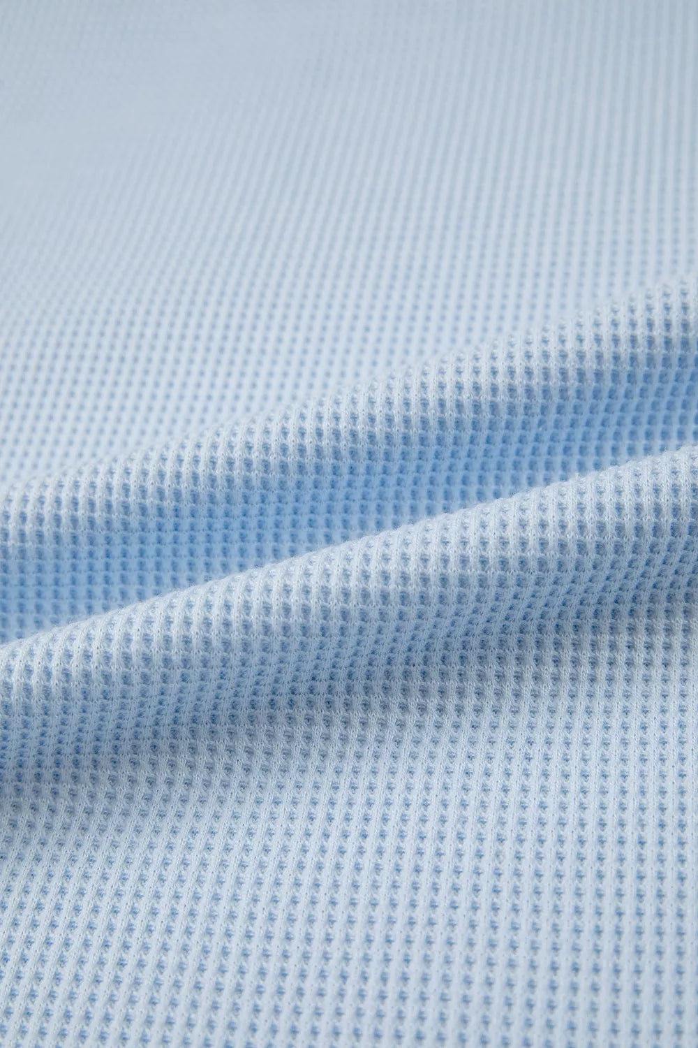 Light blue waffle knit polyester t-shirt with a textured pattern and curved hem detail.