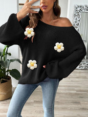 Black slouchy knit sweater with white floral appliqués and bell sleeves.