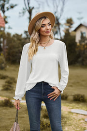 White waffle knit blouse with perforated details and ruffled cuffs.