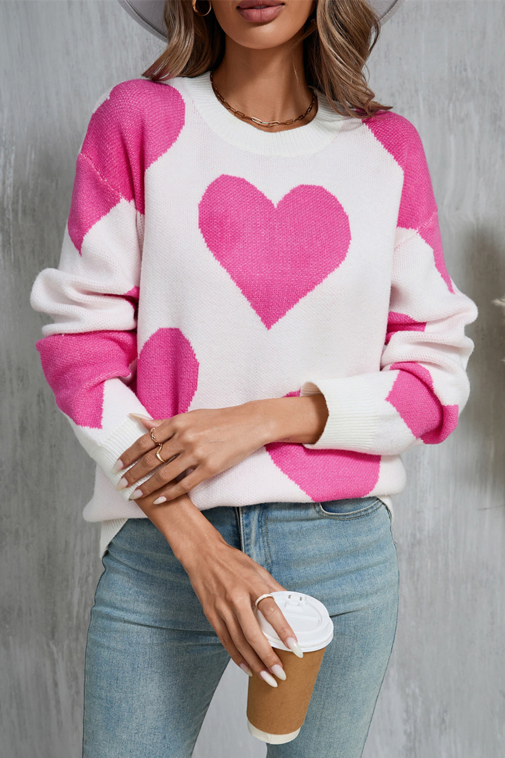 White and fuchsia pink heart patchwork knit sweater with crewneck and long sleeves.