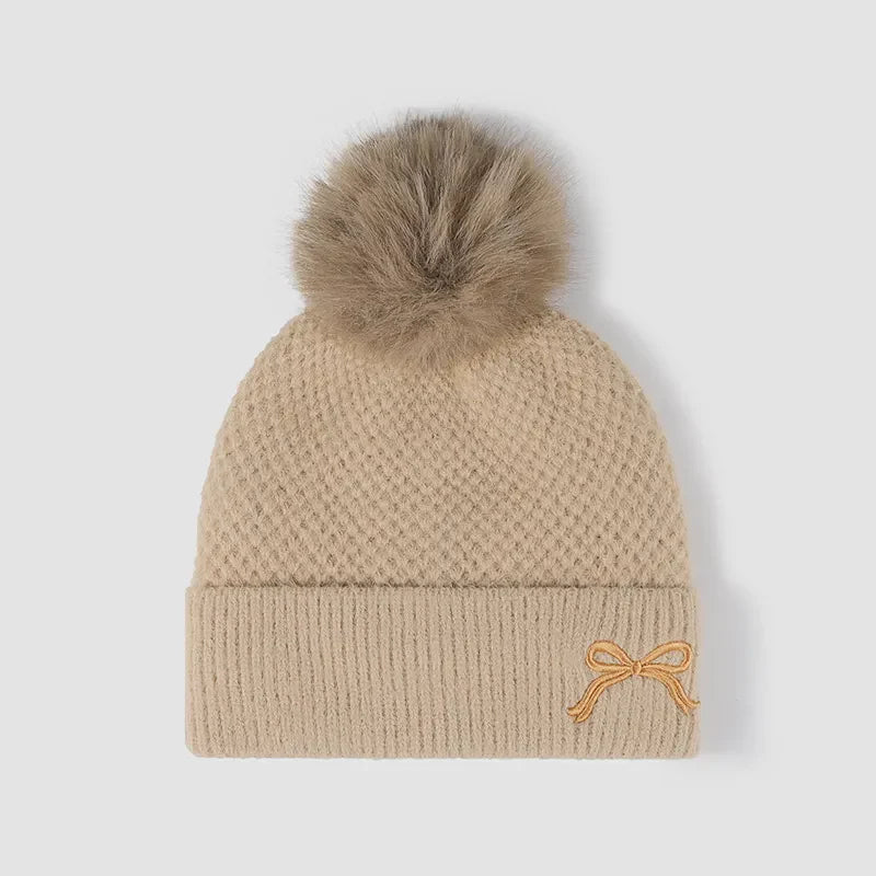 Beige knit beanie with pom-pom and embroidered bow detail