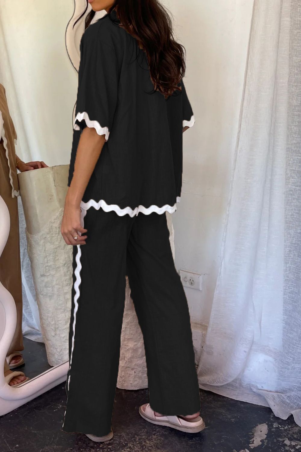 Black loungewear set with white scalloped trim on short sleeves and pant legs.