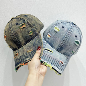 Distressed denim baseball cap with fraying and colorful accents.