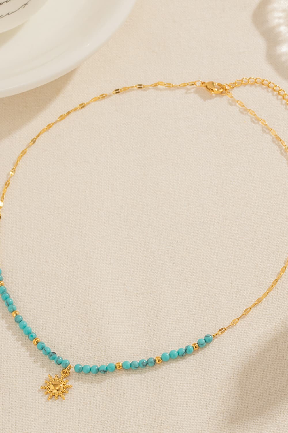 Gold celestial sunburst beaded necklace with turquoise beads and gold accents.