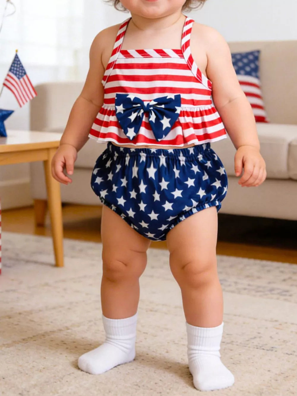 Baby outfit set with red and white striped top and blue star bloomer shorts, featuring a bow.