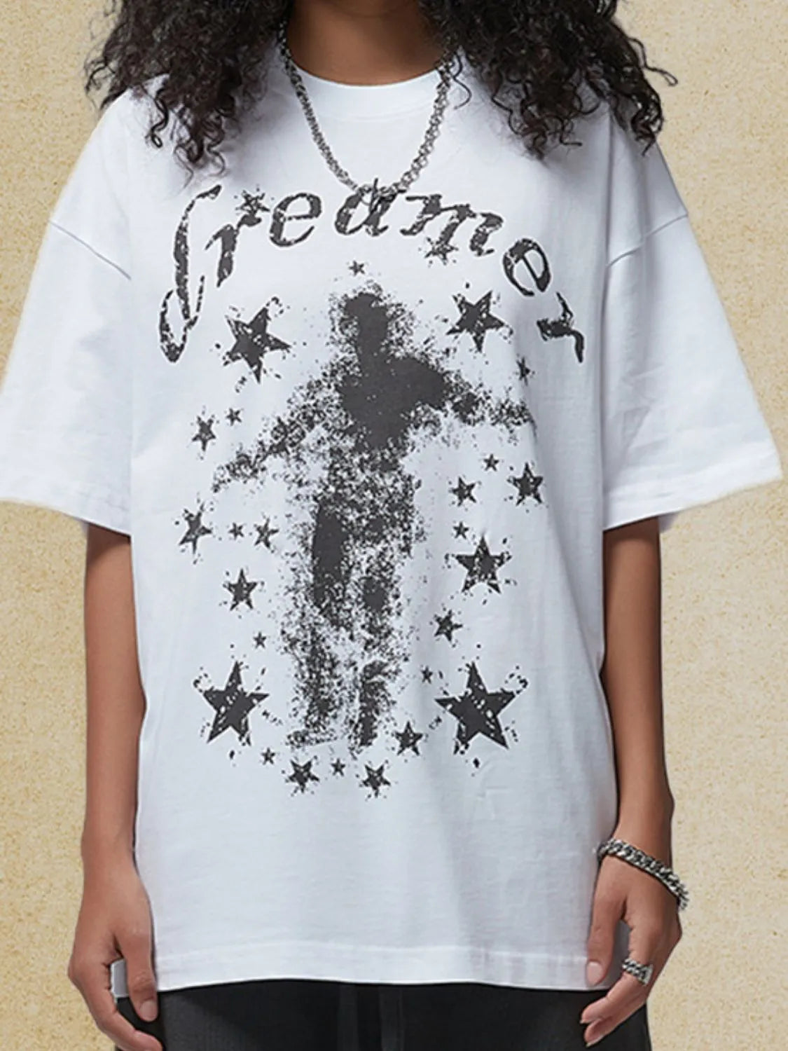 White graphic t-shirt with black "dreamer" text and a distressed figure surrounded by stars.