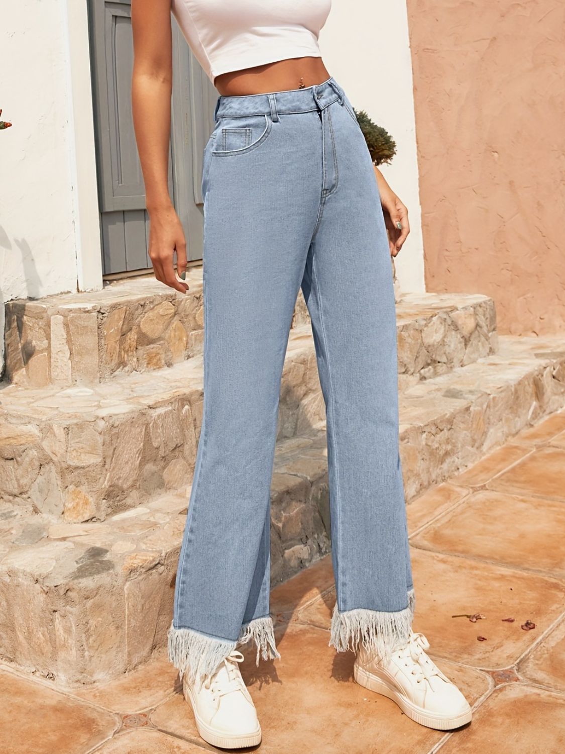 Light wash denim flare jeans with a fringed hem.