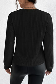 Black ribbed knit top with blouson sleeves and a cross-front detail, styled with faux leather pants.