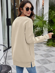 Beige tunic sweatshirt with crew neck, long sleeves, and side pockets.