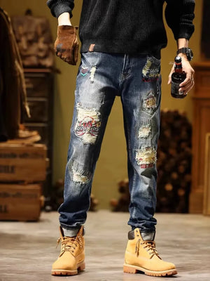 Distressed blue cotton jeans with embroidered patches and cuffed hems.