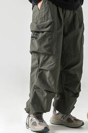 Oversized utility cargo trousers in dark gray with multiple pockets and drawstring details.