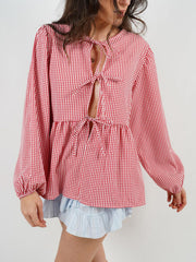 Red gingham tie-front peplum blouse with voluminous sleeves and a ruffled hem.
