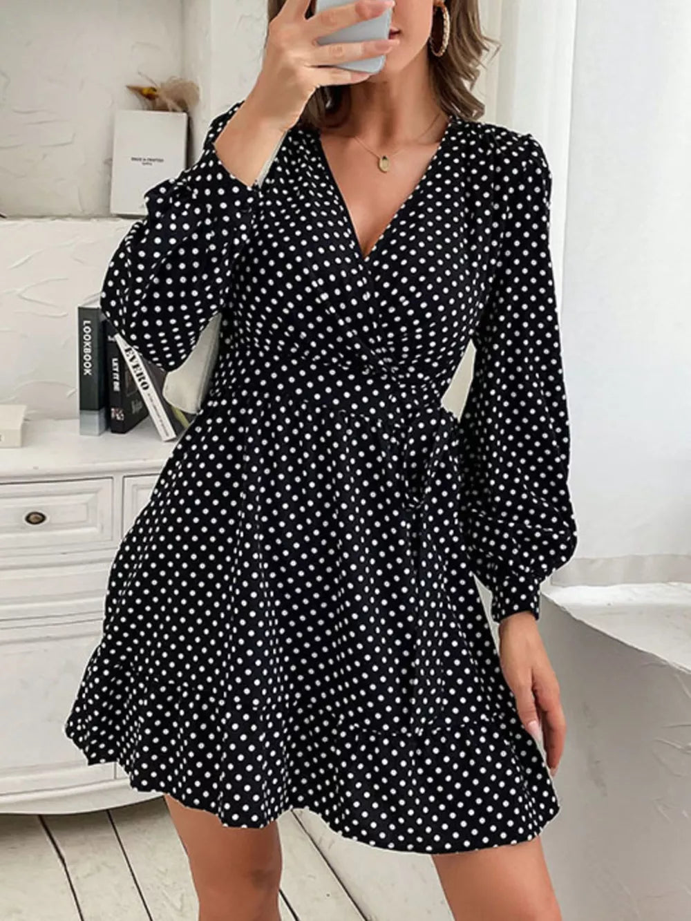 Black polka dot mini dress with V-neck, balloon sleeves, and ruffled hem.