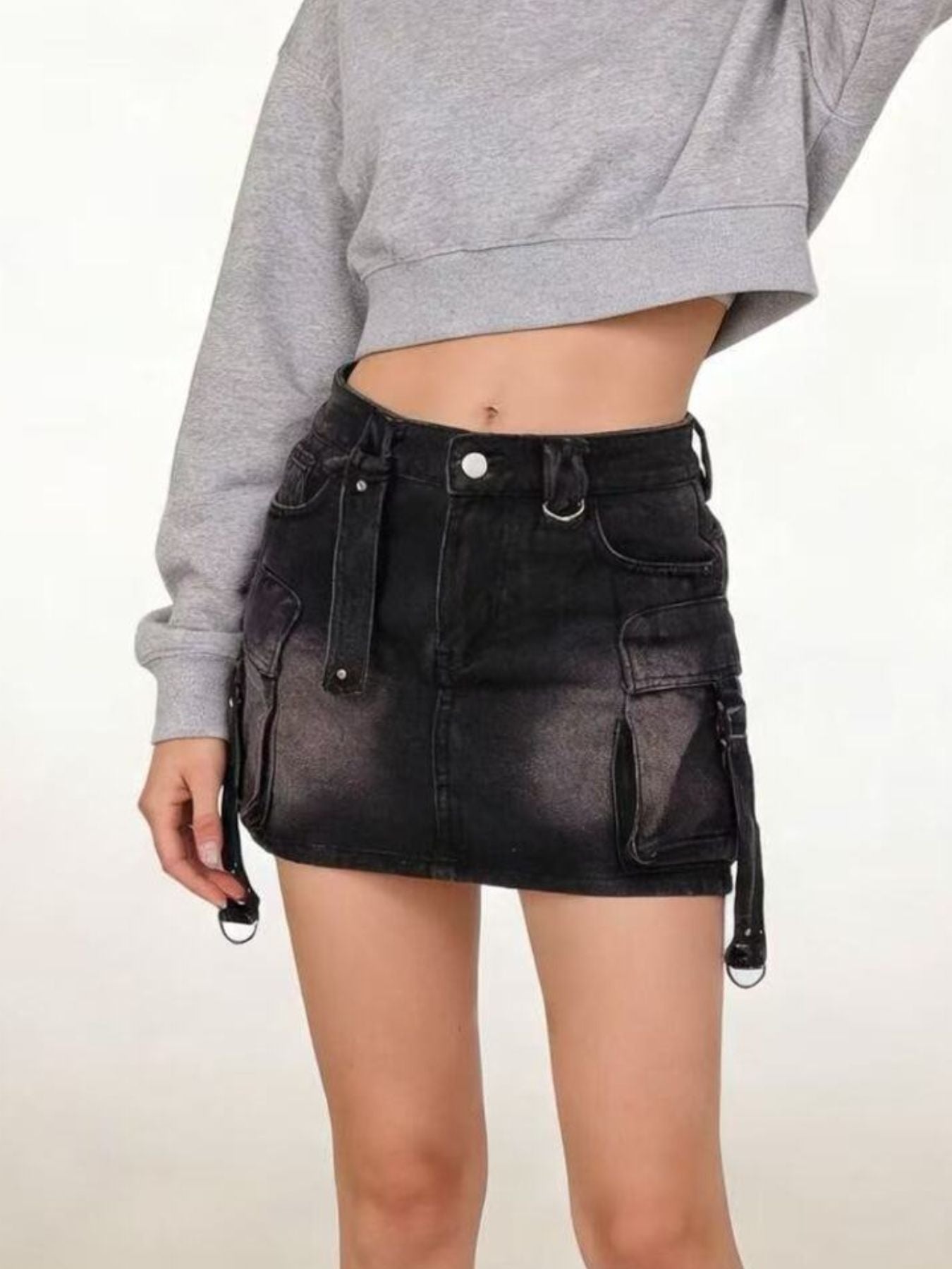 Black washed denim cargo skirt with button closure and utility straps.
